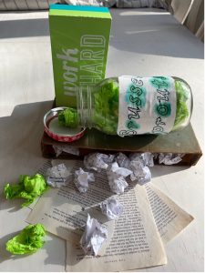 plastic bottle with crinkled sheets green paper and pages of writing